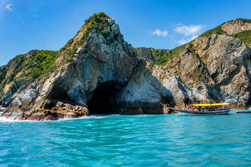 Formação rochosa imponente da Gruta Azul em mar aberto com tons de água cristalina em Arraial do Cabo.