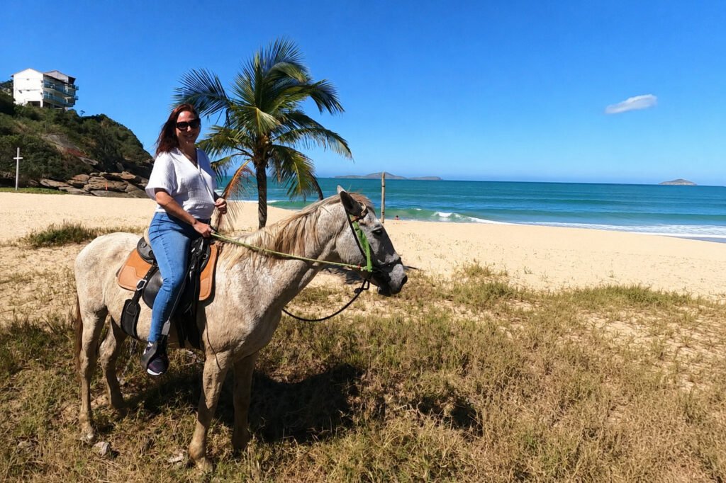 Turista montando a cavalo próximo à Praia de Caravelas durante passeio em Búzios.